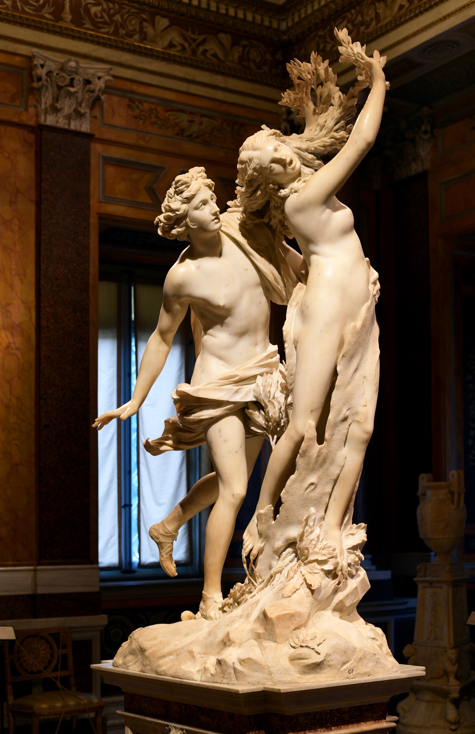 Apollo reaches for Daphne as her fingers sprout into laurel branches and bark climbs her legs — the moment of pursuit frozen at the instant transformation begins
