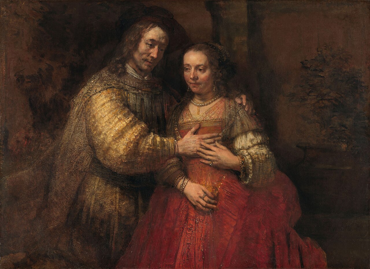 Two figures in rich golden fabric, his hand resting gently on her chest, her hand touching his — an entire relationship geometry visible in the placement of four hands